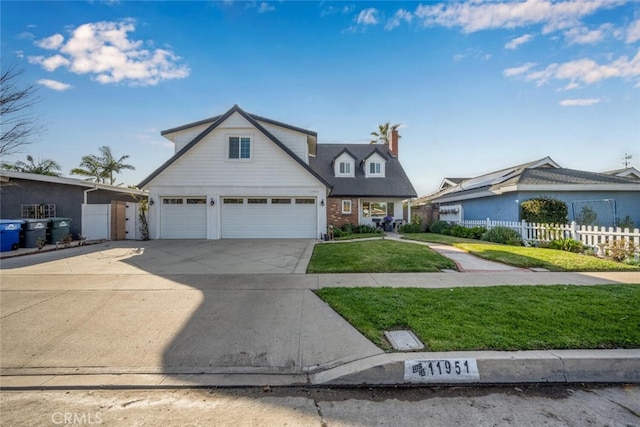 traditional-style home featuring a front yard, concrete driveway, fence, and an attached garage