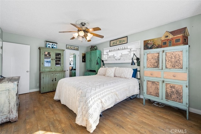 bedroom featuring ceiling fan, a textured ceiling, baseboards, and wood finished floors