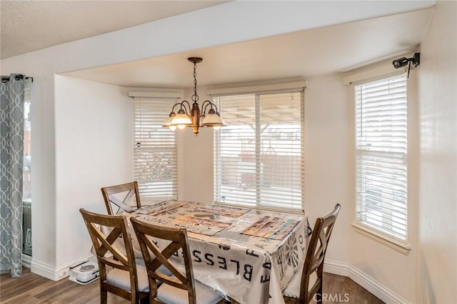 dining area with a chandelier, plenty of natural light, baseboards, and wood finished floors