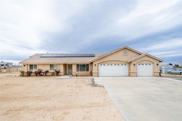 ranch-style house featuring a tiled roof, roof mounted solar panels, stucco siding, driveway, and an attached garage