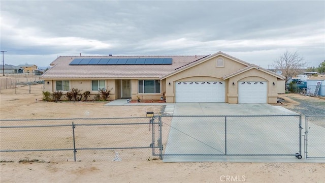 view of front facade with a gate, a fenced front yard, concrete driveway, a garage, and solar panels