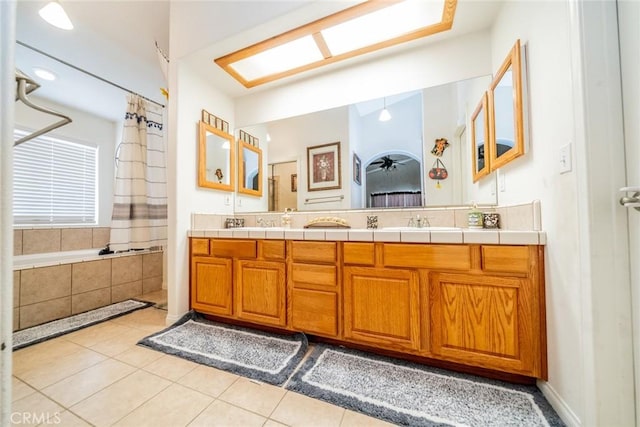 full bathroom featuring a sink, curtained shower, tile patterned flooring, double vanity, and tiled tub