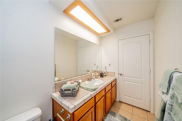 half bath with tile patterned flooring, visible vents, toilet, and vanity