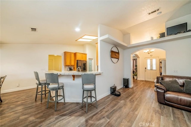 kitchen featuring a kitchen bar, arched walkways, visible vents, and stainless steel fridge with ice dispenser