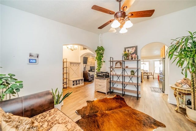 living area featuring arched walkways, a ceiling fan, and light wood-style floors