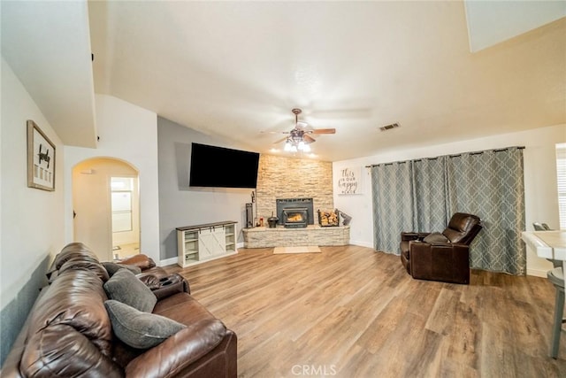 living room featuring visible vents, vaulted ceiling, wood finished floors, arched walkways, and a ceiling fan