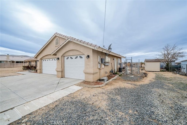 view of side of property with fence, an attached garage, stucco siding, concrete driveway, and a tiled roof