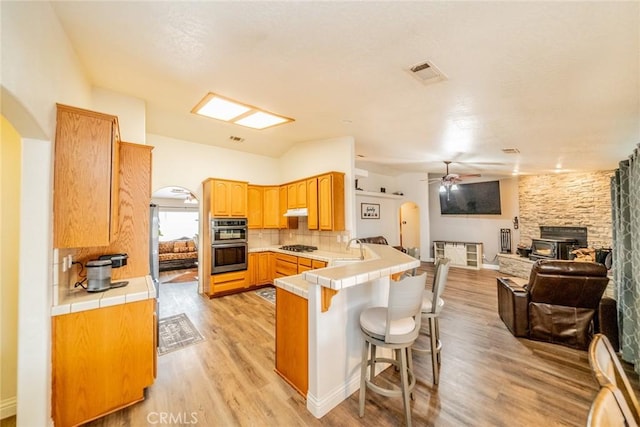 kitchen featuring arched walkways, visible vents, and a peninsula