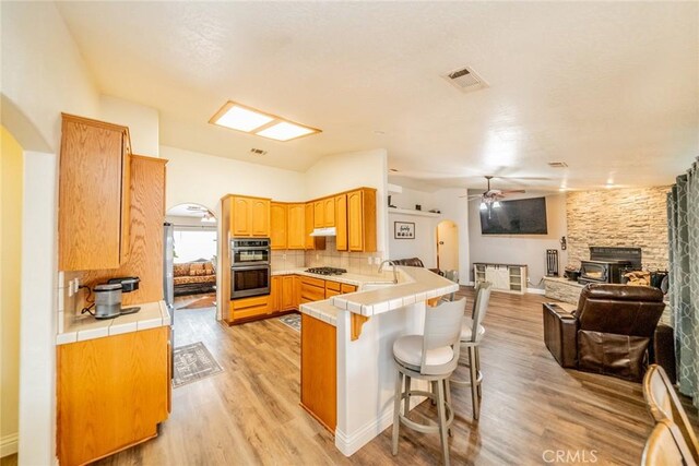11130 Tenaya Rd, Apple Valley, CA 92308 - kitchen with arched walkways, a peninsula, tile counters, and stainless steel double oven