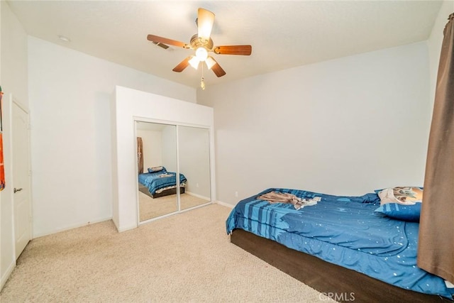 carpeted bedroom with a closet, visible vents, and ceiling fan