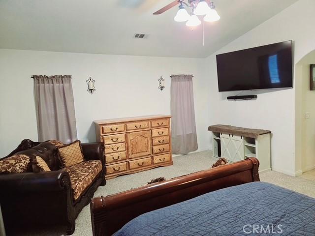 bedroom featuring visible vents, a ceiling fan, carpet, and vaulted ceiling