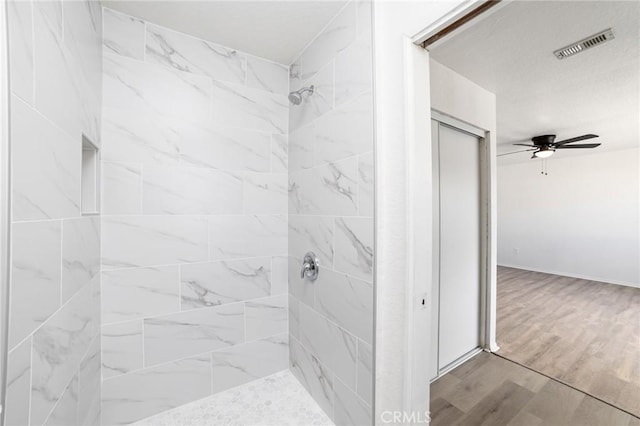 full bathroom featuring wood finished floors, walk in shower, visible vents, and a ceiling fan