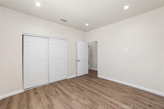unfurnished bedroom featuring baseboards, visible vents, wood finished floors, a closet, and recessed lighting