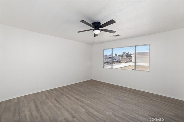 spare room with visible vents, ceiling fan, a textured ceiling, wood finished floors, and baseboards
