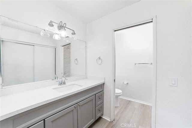bathroom with baseboards, vanity, toilet, and wood finished floors