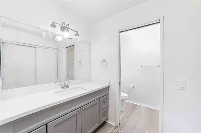 full bath featuring toilet, baseboards, wood finished floors, and vanity