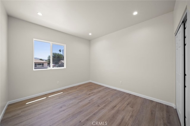 unfurnished bedroom with baseboards, a closet, wood finished floors, and recessed lighting