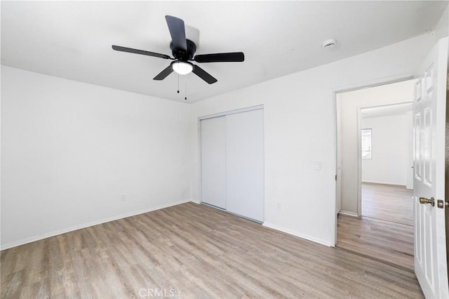 unfurnished bedroom featuring a closet, ceiling fan, baseboards, and wood finished floors