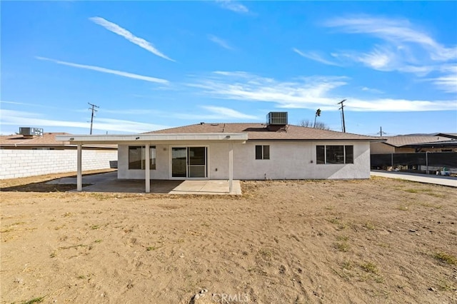 rear view of property featuring a patio, central AC, fence, and stucco siding