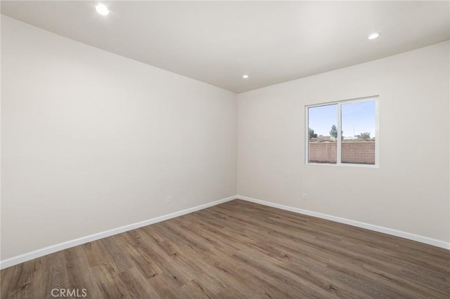 spare room with recessed lighting, wood finished floors, and baseboards