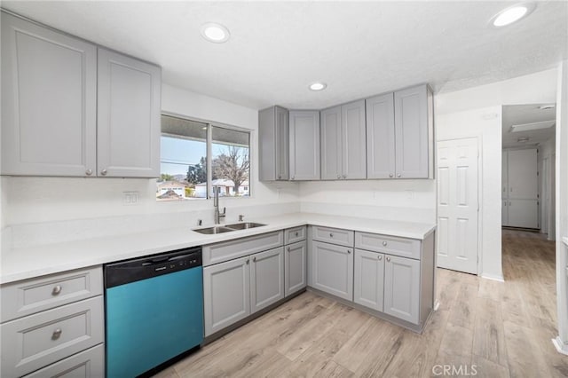 kitchen featuring dishwasher, light wood-style flooring, light countertops, gray cabinetry, and a sink