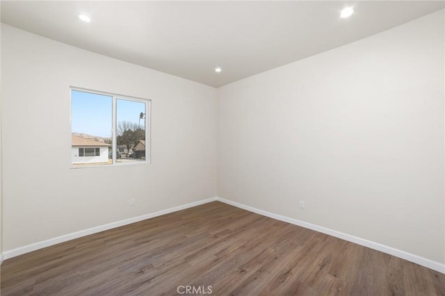 empty room featuring recessed lighting, wood finished floors, and baseboards