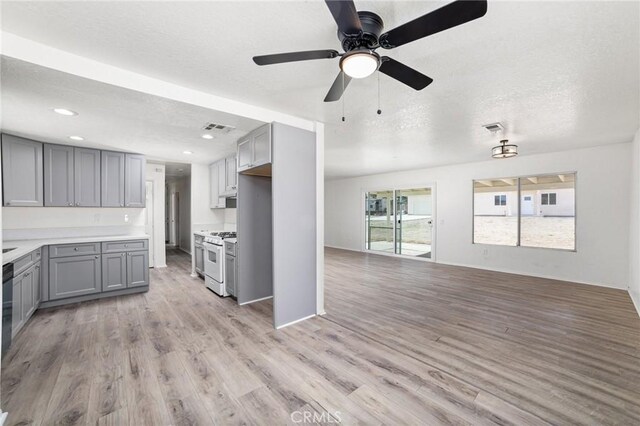 kitchen featuring white gas range, gray cabinets, visible vents, light wood-style floors, and open floor plan