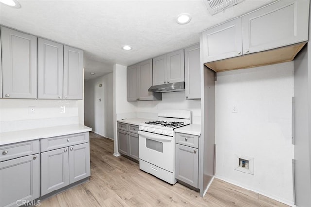 kitchen with gray cabinetry, under cabinet range hood, visible vents, and white range with gas stovetop