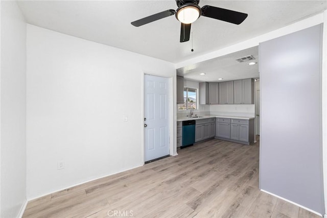 interior space featuring dishwashing machine, a sink, visible vents, gray cabinets, and light wood finished floors