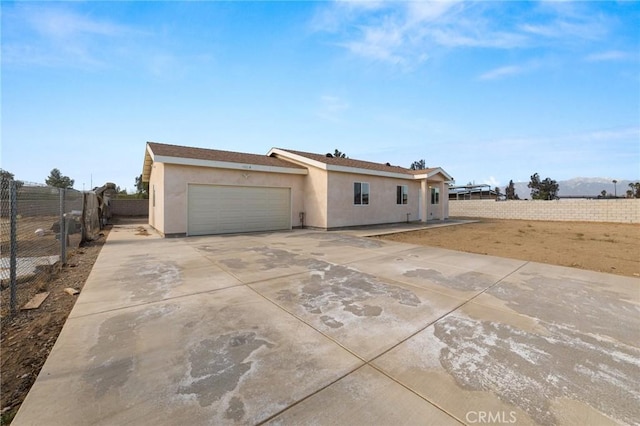 view of front of house with a garage, concrete driveway, fence, and stucco siding
