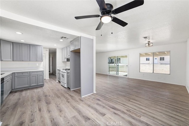 kitchen featuring white range with gas cooktop, visible vents, open floor plan, gray cabinetry, and light wood-style floors