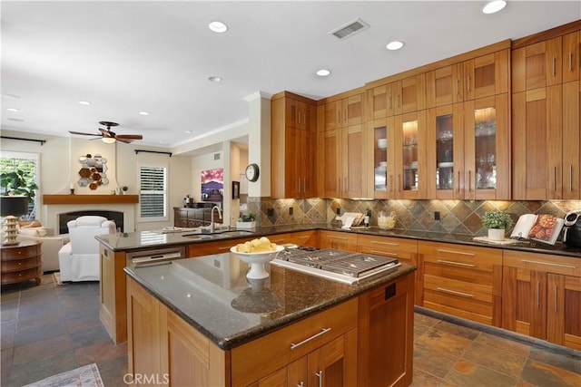 kitchen with tasteful backsplash, a center island, visible vents, and a sink