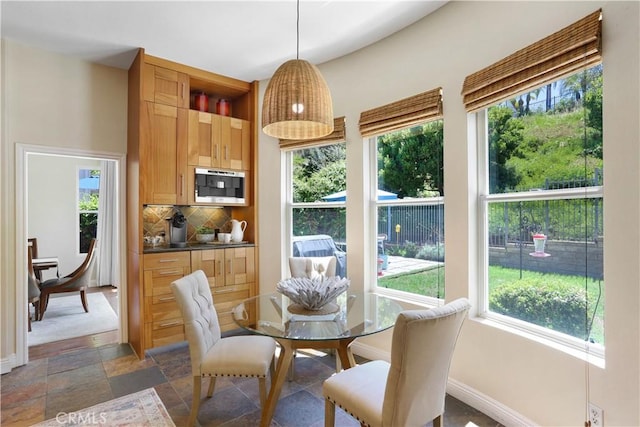 dining room featuring a healthy amount of sunlight, baseboards, and stone finish floor