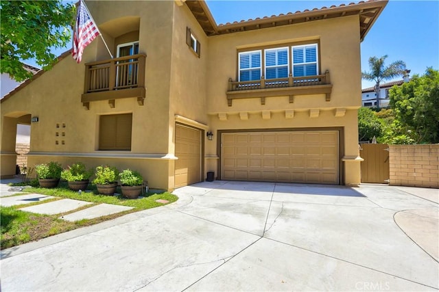 mediterranean / spanish-style house with concrete driveway, an attached garage, a balcony, and stucco siding