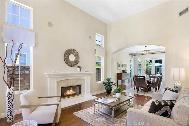 living room featuring baseboards, wood finished floors, visible vents, and a healthy amount of sunlight