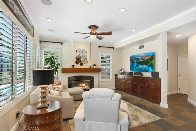 living area with recessed lighting, visible vents, ornamental molding, a glass covered fireplace, and baseboards