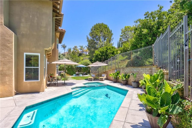 view of swimming pool featuring a patio area, fence, and a pool with connected hot tub