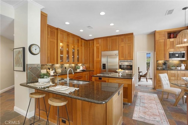 kitchen featuring visible vents, glass insert cabinets, a sink, stainless steel appliances, and backsplash