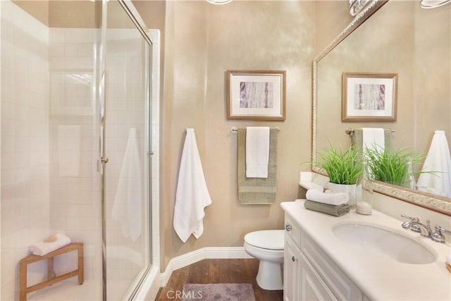 bathroom with a stall shower, vanity, toilet, and wood finished floors