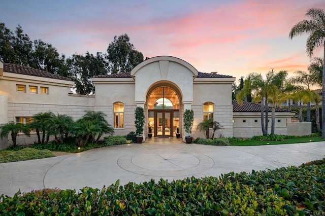 view of front facade featuring driveway, french doors, and stucco siding