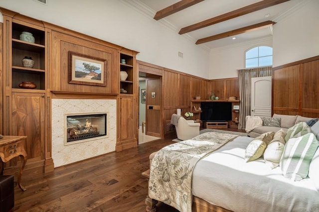 bedroom with visible vents, dark wood-type flooring, beam ceiling, wainscoting, and a fireplace