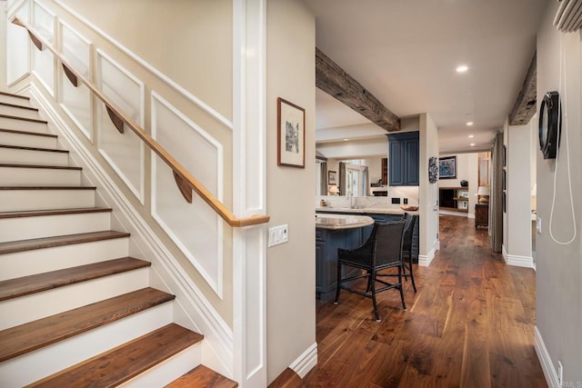 staircase featuring baseboards, beam ceiling, wood finished floors, and recessed lighting
