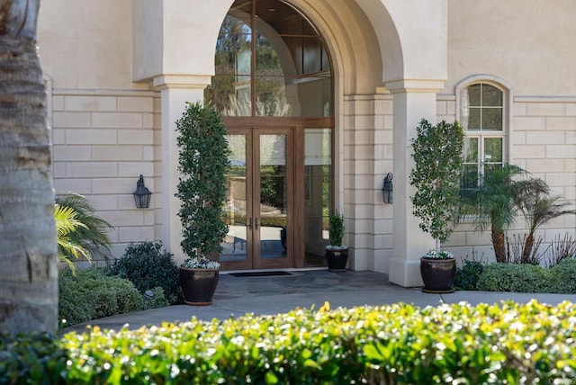 view of exterior entry featuring stucco siding and french doors