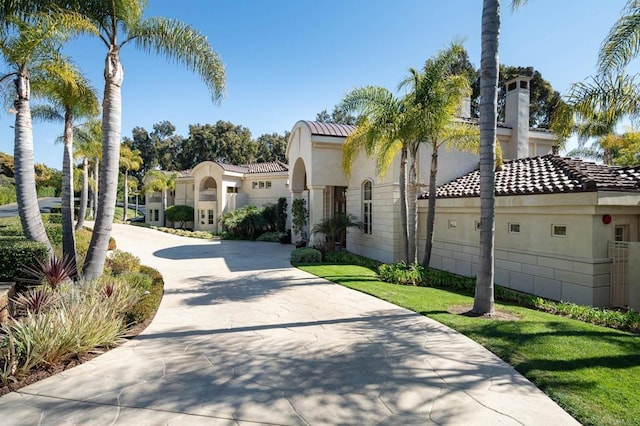 mediterranean / spanish house featuring concrete driveway, a tiled roof, and stucco siding