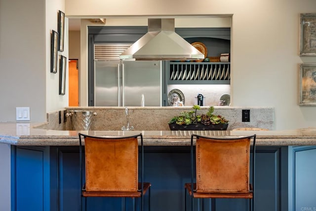14479 Emerald Ln, Rancho Santa Fe, CA 92067 - kitchen with built in refrigerator, blue cabinets, island range hood, and light stone countertops