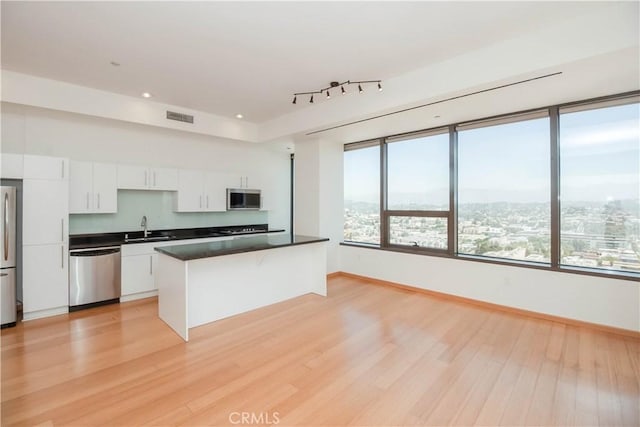 kitchen with visible vents, white cabinets, dark countertops, appliances with stainless steel finishes, and a sink