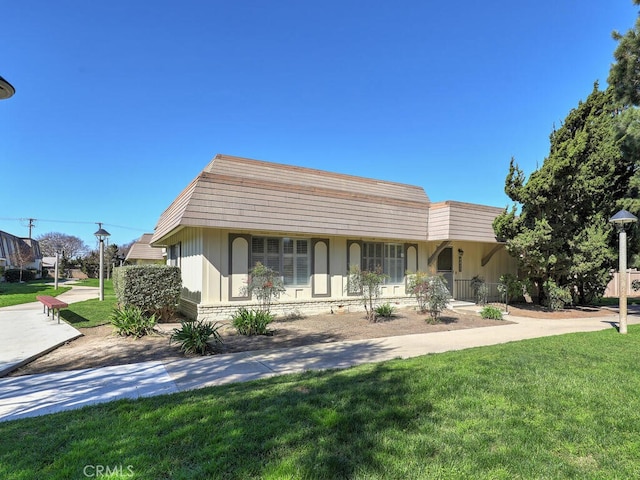 view of front of home with a front lawn and mansard roof