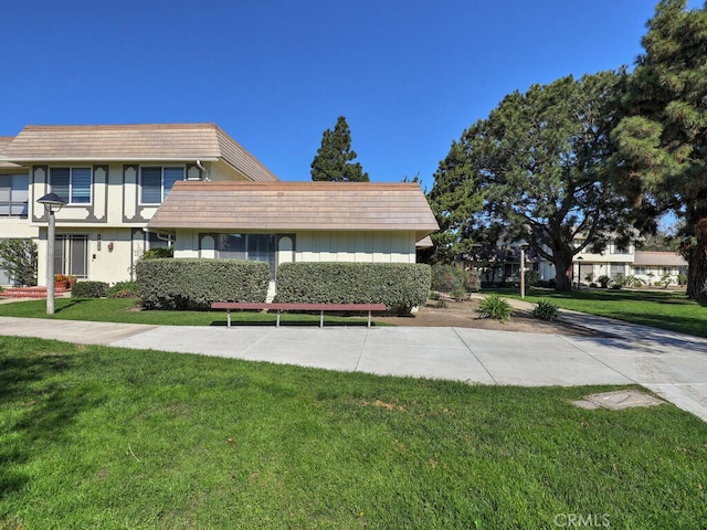 view of front facade with a front yard and mansard roof