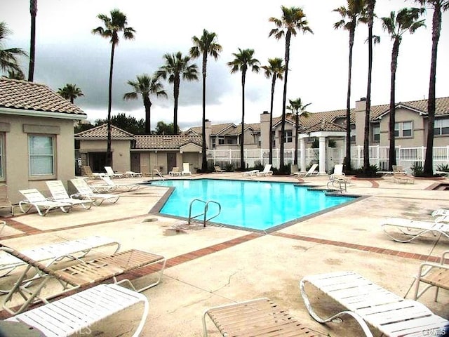 pool with a residential view, fence, and a patio