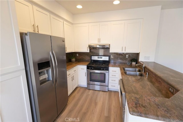 kitchen with stainless steel appliances, decorative backsplash, a sink, a peninsula, and under cabinet range hood